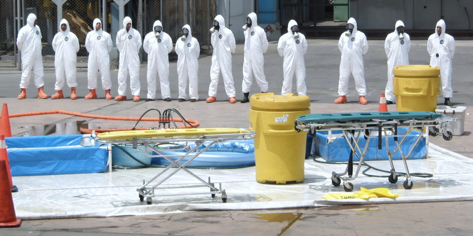 Responders in protective suits and respirators lined up at a decontamination station